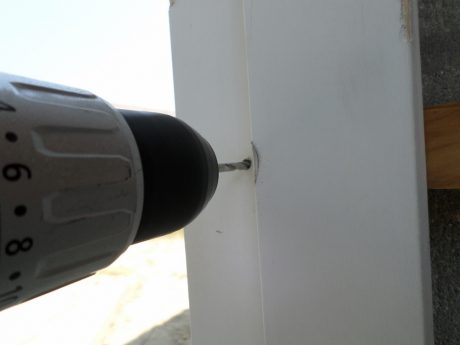 Drilling through the door frame, door buck and concrete block. Note we removed the weatherstripping to install the Tapcon