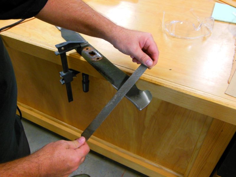 Hand sharpening a lawn mower blade.