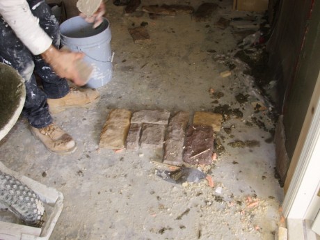 Ugly Randy is laying out the stones on the floor before he puts them on the wall