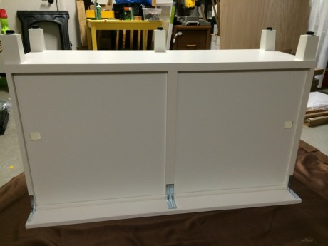 I've actually got two L-brackets in the center, because I'm going to cut the trim board in half. You can also see the holes I put in the back of the bottom frame to accomodate wires coming from various electronic devices.